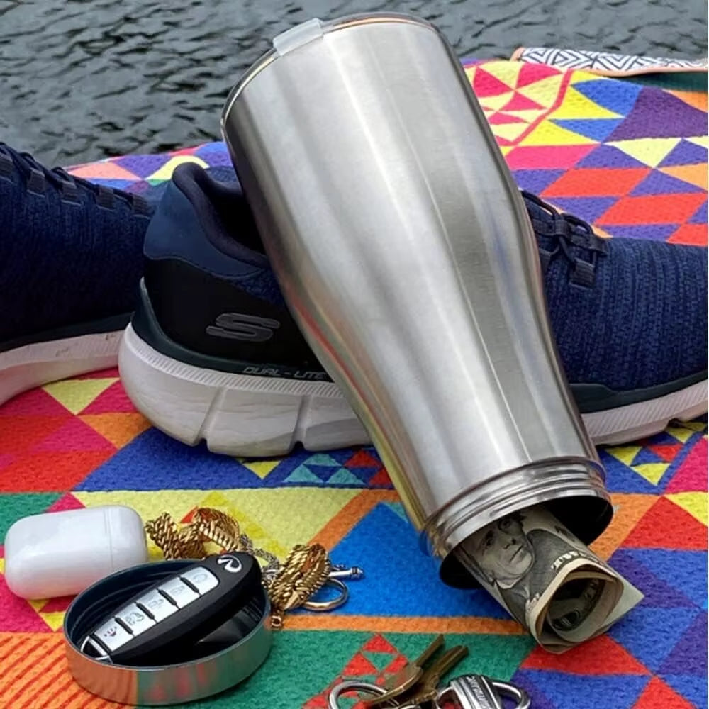 Mug inox avec compartiment caché contenant argent et clés, posé sur une serviette colorée, idéal pour ranger discrètement ses objets de valeur.