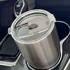 Mug inox isotherme avec couvercle transparent posé dans un porte-gobelet de voiture, idéal pour garder sa boisson chaude ou froide.